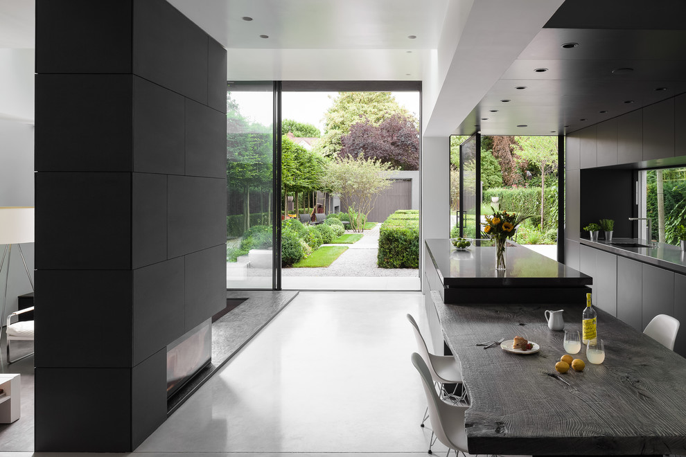 Photo of an expansive contemporary single-wall open plan kitchen in London with a built-in sink, flat-panel cabinets, grey cabinets, composite countertops, integrated appliances, concrete flooring, an island and grey floors.