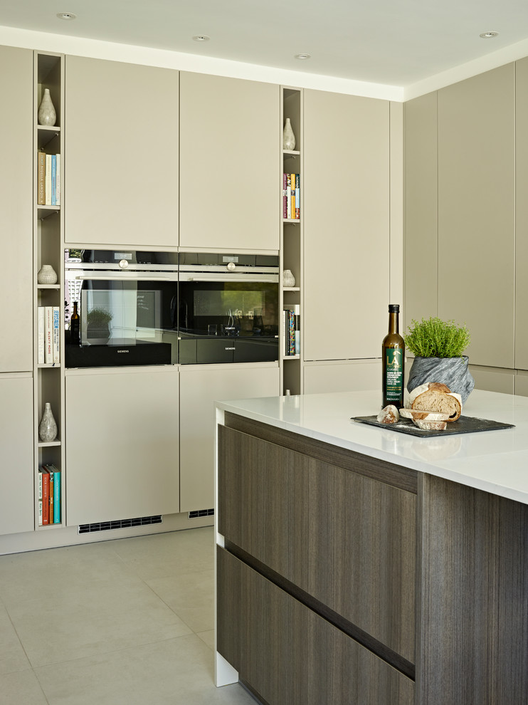 This is an example of a medium sized contemporary l-shaped kitchen/diner in London with a built-in sink, flat-panel cabinets, beige cabinets, composite countertops, brown splashback, stainless steel appliances, porcelain flooring, an island, grey floors and white worktops.
