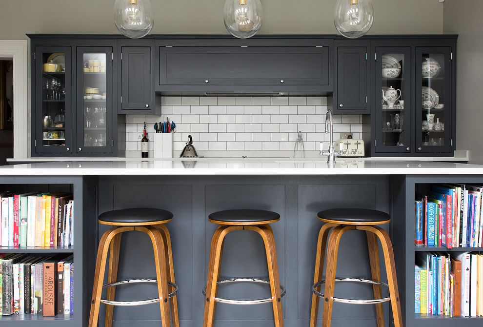 Design ideas for a traditional open plan kitchen in London with a built-in sink, shaker cabinets, dark wood cabinets, white splashback, ceramic splashback, black appliances and an island.