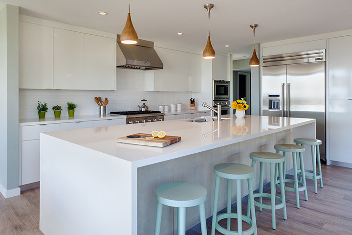 Large modern l-shaped kitchen/diner in Phoenix with flat-panel cabinets, white cabinets, white splashback, stainless steel appliances, an island, a submerged sink, engineered stone countertops, metro tiled splashback and porcelain flooring.
