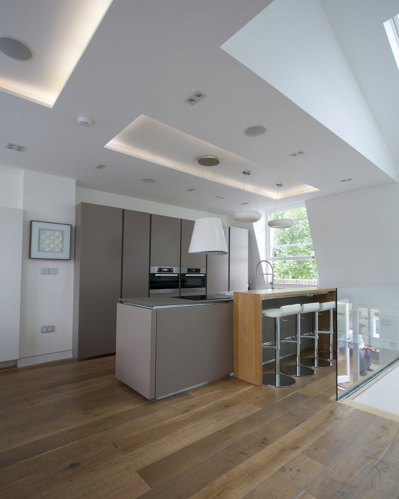 Offene, Zweizeilige Moderne Küche mit Küchengeräten aus Edelstahl, braunem Holzboden, Kücheninsel und Arbeitsplatte aus Holz in London