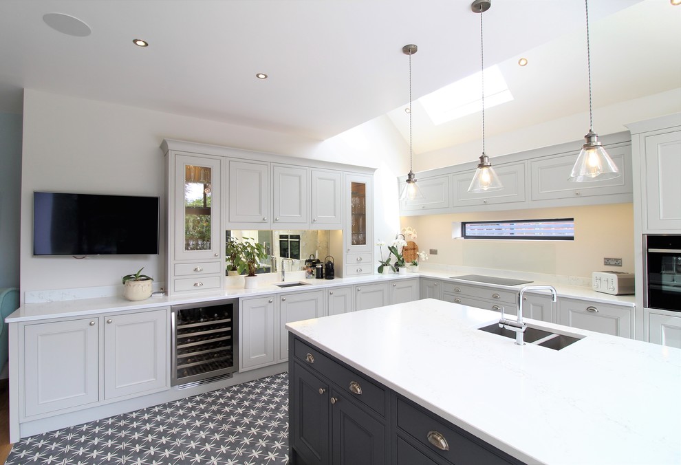 Bild på ett stort funkis vit vitt kök, med luckor med profilerade fronter, grå skåp, bänkskiva i kvartsit och en köksö