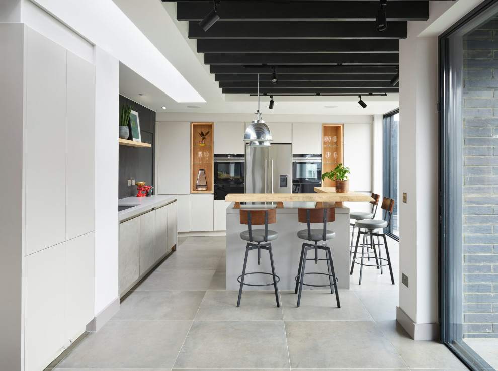 Inspiration for a contemporary l-shaped open plan kitchen in London with concrete worktops, an island, a submerged sink, flat-panel cabinets, grey cabinets, black splashback, stainless steel appliances, concrete flooring, grey floors and grey worktops.