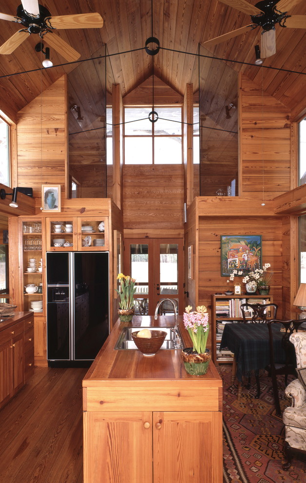Cette photo montre une cuisine ouverte parallèle tendance en bois brun de taille moyenne avec un évier 2 bacs, un plan de travail en bois, un sol en bois brun et îlot.
