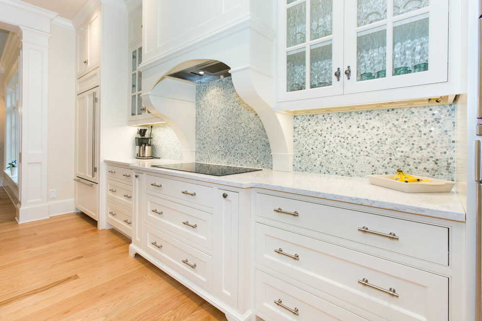 Exempel på ett mellanstort klassiskt linjärt kök och matrum, med en undermonterad diskho, luckor med profilerade fronter, vita skåp, bänkskiva i kvartsit, blått stänkskydd, stänkskydd i mosaik, integrerade vitvaror, ljust trägolv och en köksö