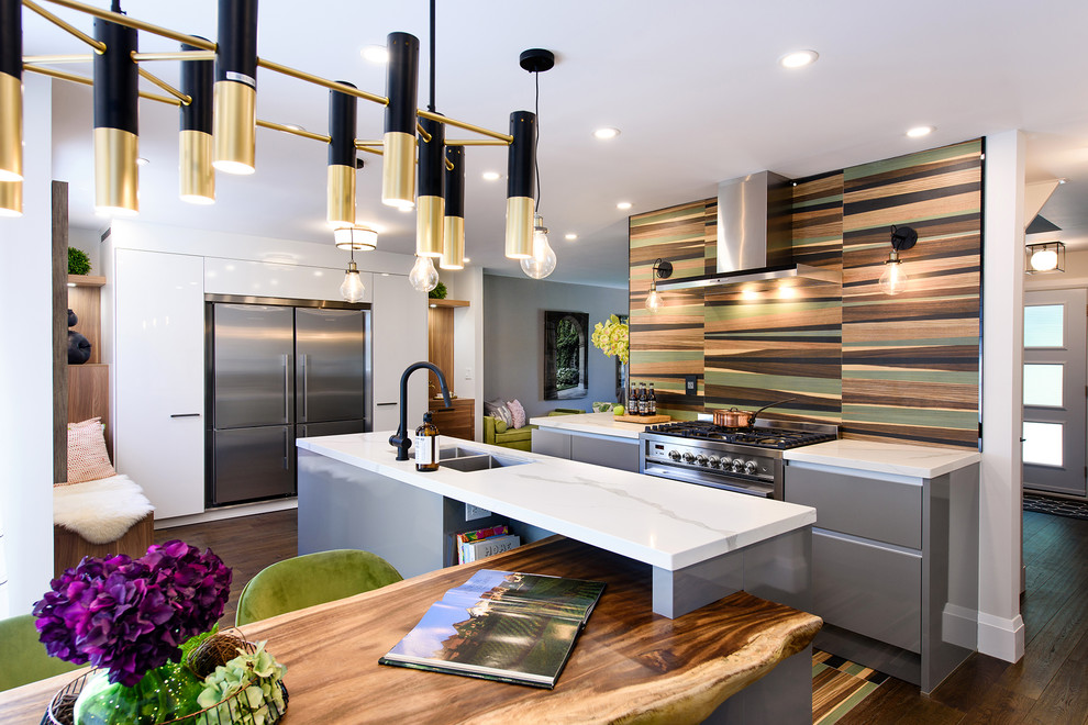 Small contemporary kitchen/diner in Toronto with a built-in sink, flat-panel cabinets, grey cabinets, multi-coloured splashback, stainless steel appliances, an island, brown floors and white worktops.