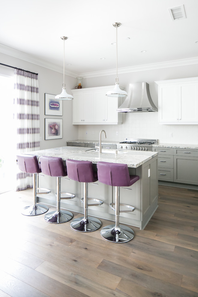 This is an example of a medium sized traditional grey and purple l-shaped kitchen/diner in Orange County with a submerged sink, shaker cabinets, grey cabinets, quartz worktops, white splashback, ceramic splashback, stainless steel appliances, medium hardwood flooring, an island, brown floors and grey worktops.