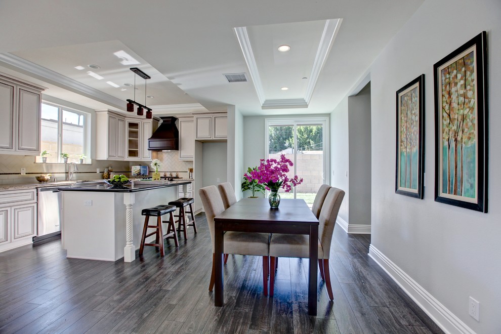 Eat-in kitchen - mid-sized transitional l-shaped dark wood floor eat-in kitchen idea in Orange County with beaded inset cabinets, white cabinets, white backsplash, stainless steel appliances and an island