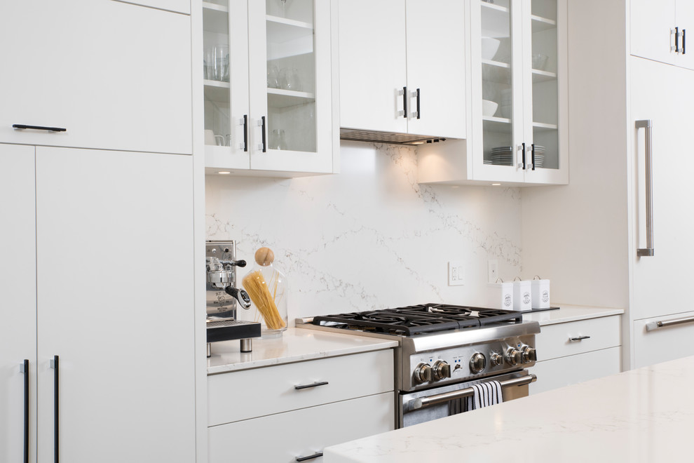 This is an example of a medium sized traditional galley open plan kitchen in Vancouver with a submerged sink, flat-panel cabinets, white cabinets, quartz worktops, white splashback, stone slab splashback, integrated appliances, light hardwood flooring, an island and beige floors.
