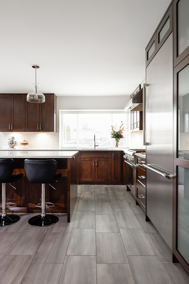 Foto di una cucina moderna di medie dimensioni con lavello sottopiano, ante in stile shaker, ante in legno bruno, paraspruzzi beige, elettrodomestici in acciaio inossidabile, pavimento grigio e top bianco