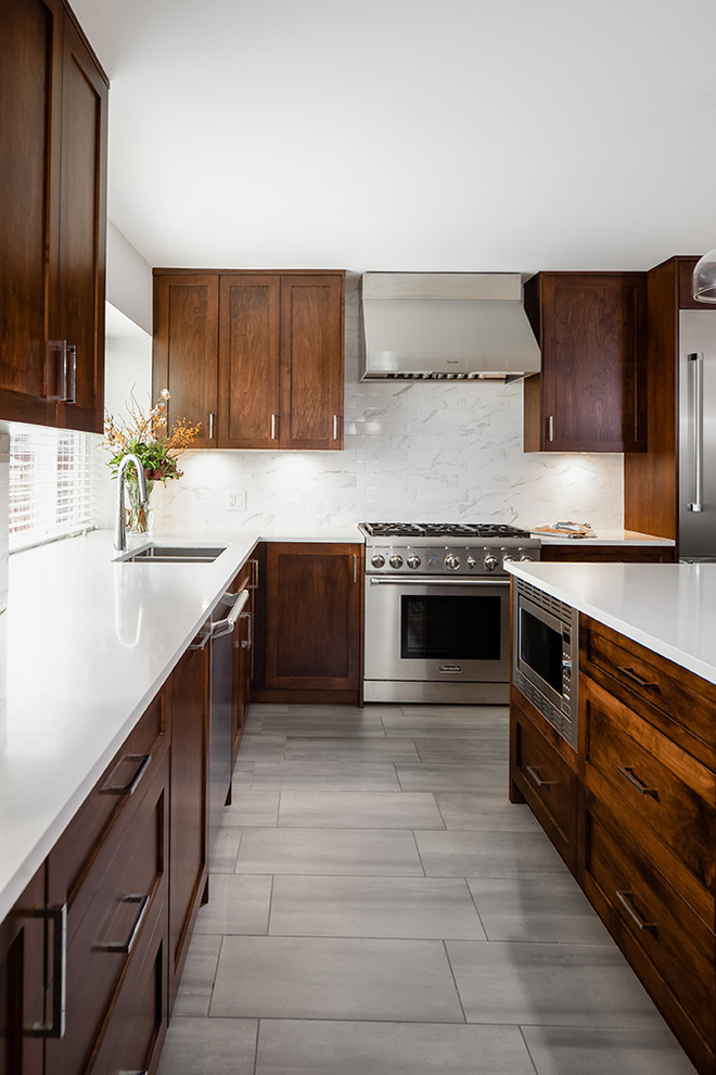 Esempio di una cucina moderna di medie dimensioni con lavello sottopiano, ante in stile shaker, ante in legno bruno, paraspruzzi beige, elettrodomestici in acciaio inossidabile, pavimento grigio e top bianco