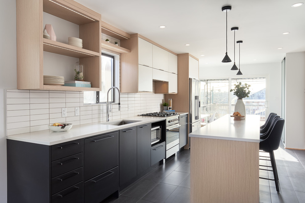 Zweizeilige Moderne Küche mit Unterbauwaschbecken, flächenbündigen Schrankfronten, schwarzen Schränken, Küchenrückwand in Weiß, Küchengeräten aus Edelstahl, Kücheninsel, schwarzem Boden und weißer Arbeitsplatte in Vancouver