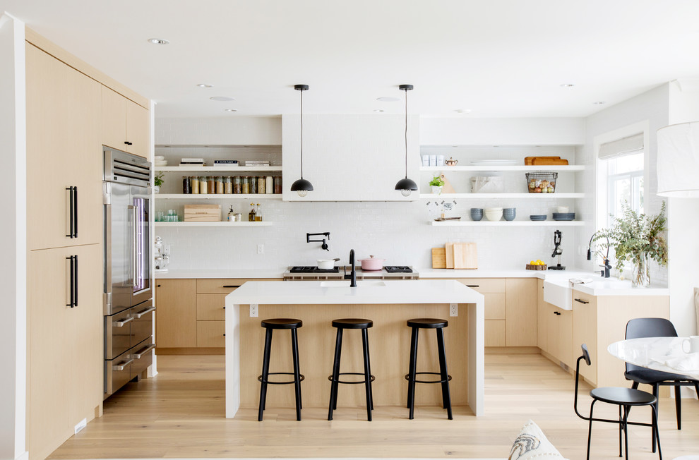 Moderne Wohnküche in U-Form mit Landhausspüle, flächenbündigen Schrankfronten, hellen Holzschränken, Küchenrückwand in Weiß, Küchengeräten aus Edelstahl, hellem Holzboden, Kücheninsel, beigem Boden und gelber Arbeitsplatte in Vancouver