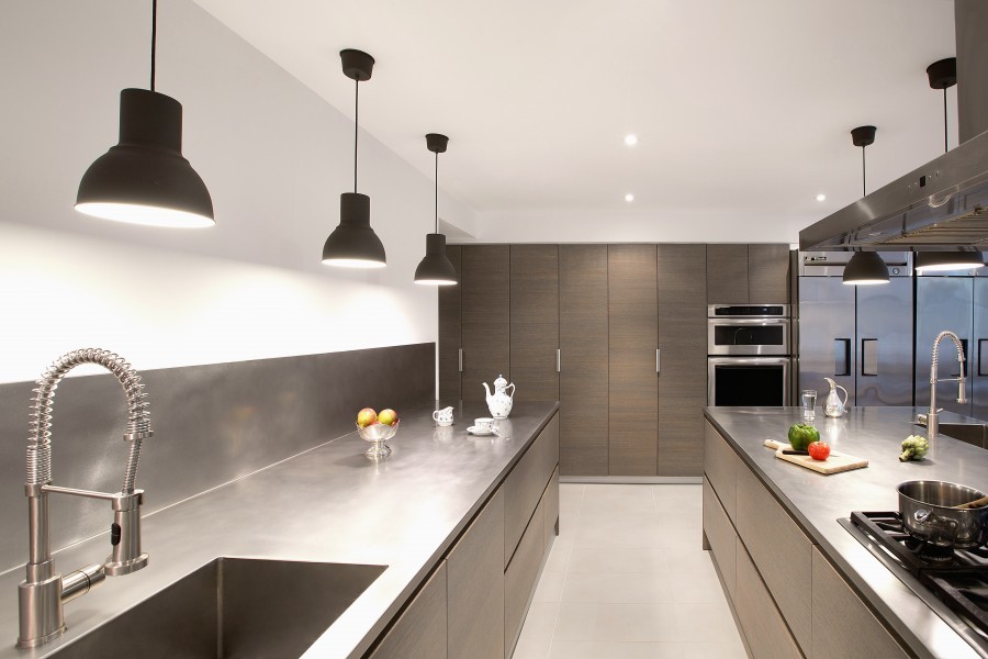 This is an example of a large contemporary enclosed kitchen in New York with flat-panel cabinets, an integrated sink, grey cabinets, stainless steel worktops, metallic splashback, stainless steel appliances, porcelain flooring and a breakfast bar.
