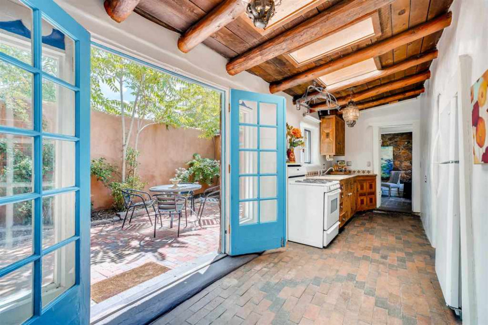 Mediterrane Küche mit Backsteinboden, rotem Boden und freigelegten Dachbalken in Albuquerque