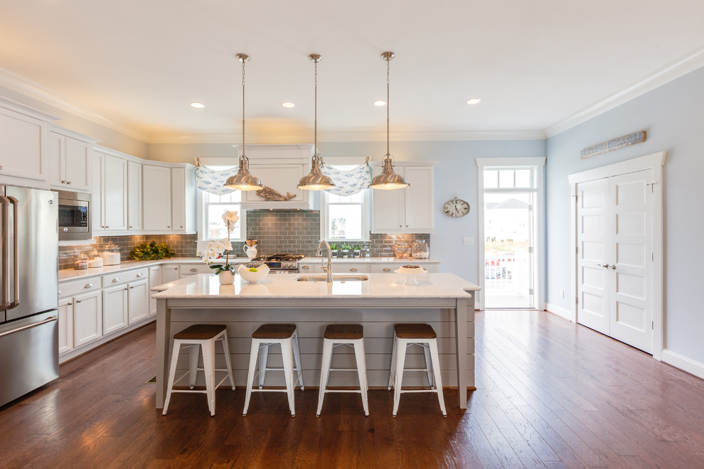 Large beach style l-shaped medium tone wood floor open concept kitchen photo in Other with an undermount sink, shaker cabinets, white cabinets, quartz countertops, blue backsplash, glass tile backsplash, stainless steel appliances and an island