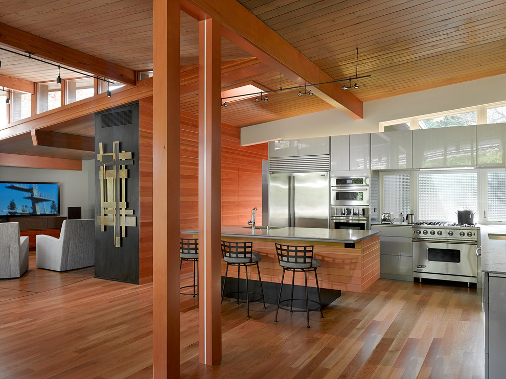 Offene Moderne Küche in L-Form mit Unterbauwaschbecken, flächenbündigen Schrankfronten, weißen Schränken, Küchengeräten aus Edelstahl, braunem Holzboden und Kücheninsel in San Francisco