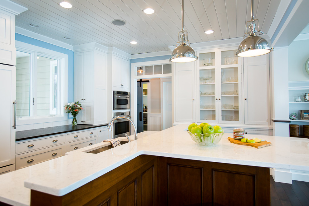 Exempel på ett mellanstort maritimt kök, med en undermonterad diskho, luckor med infälld panel, vita skåp, granitbänkskiva, vitt stänkskydd, stänkskydd i tunnelbanekakel, rostfria vitvaror, mörkt trägolv och en köksö