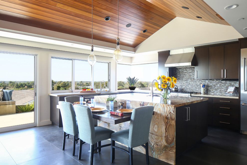 Photo of a large contemporary u-shaped kitchen/diner in Orange County with flat-panel cabinets, dark wood cabinets, engineered stone countertops, multi-coloured splashback, stainless steel appliances, porcelain flooring, an island and matchstick tiled splashback.