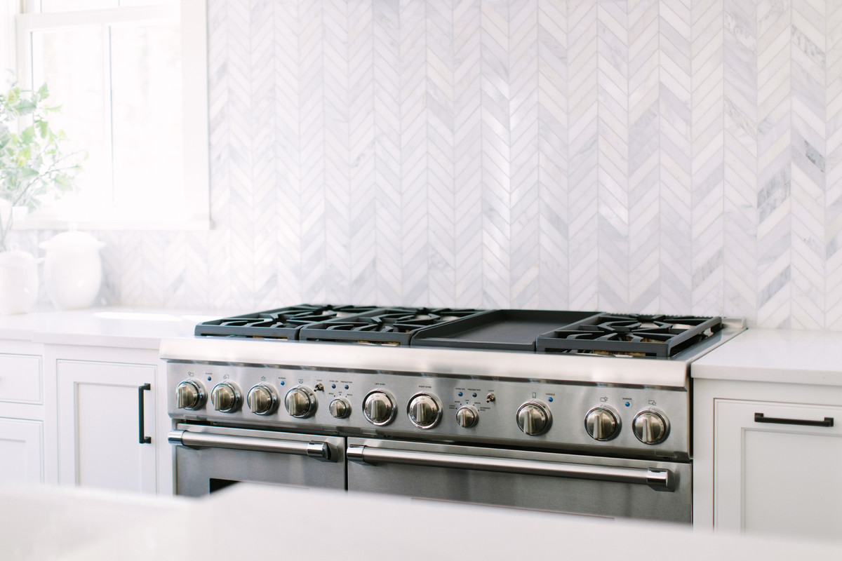 Foto di una cucina classica con ante in stile shaker, ante bianche, paraspruzzi bianco, paraspruzzi in marmo, elettrodomestici da incasso, parquet scuro e pavimento marrone