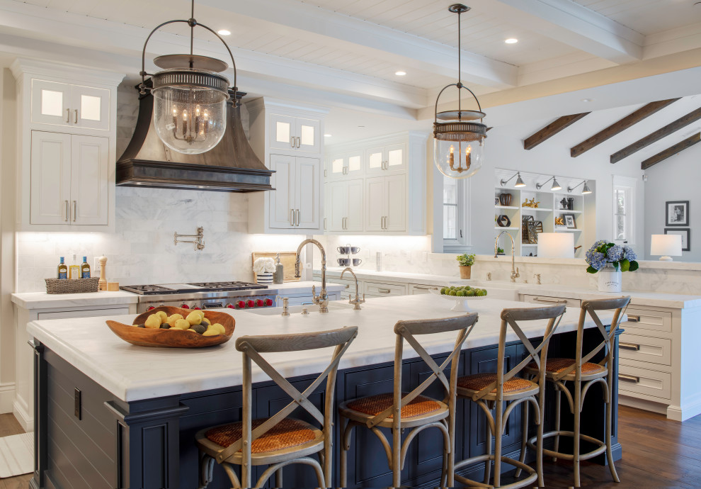 Inspiration for an expansive beach style open plan kitchen in San Francisco with a belfast sink, beaded cabinets, white cabinets, marble worktops, white splashback, marble splashback, integrated appliances, dark hardwood flooring, an island, brown floors, white worktops and exposed beams.