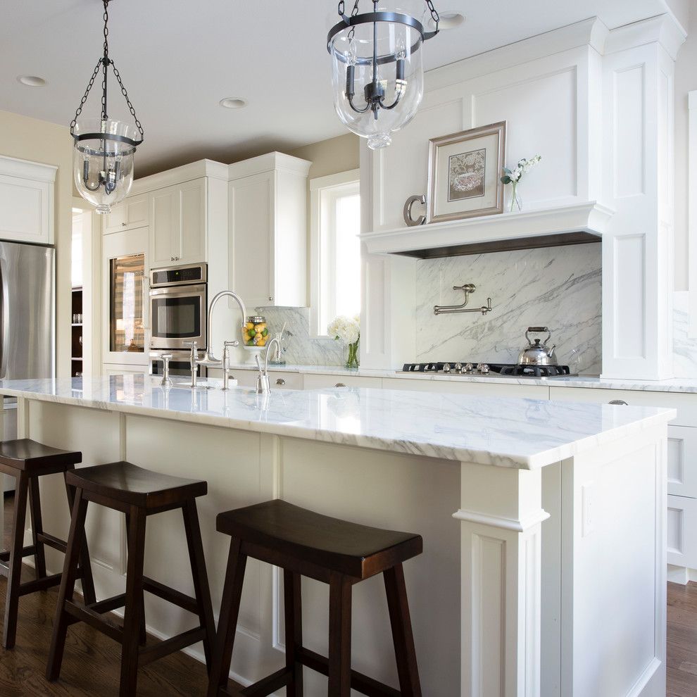 Inspiration for a large timeless dark wood floor and brown floor eat-in kitchen remodel in Denver with a farmhouse sink, recessed-panel cabinets, white cabinets, marble countertops, white backsplash, marble backsplash, stainless steel appliances, an island and white countertops