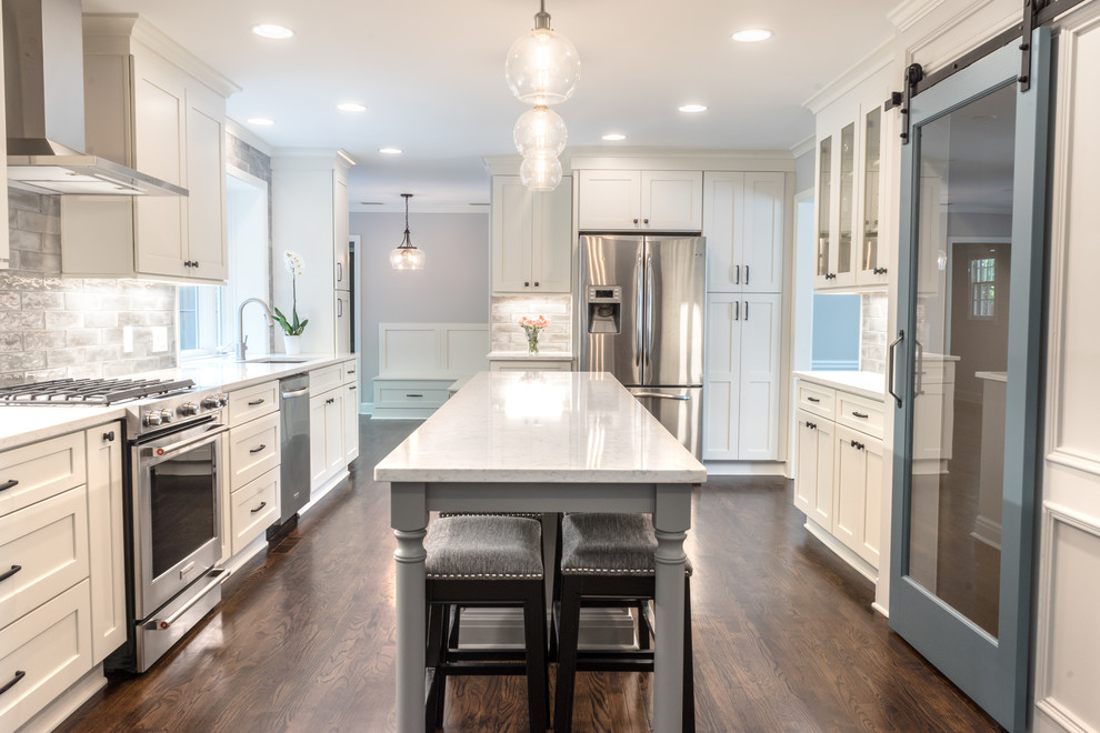 Inspiration for a large modern u-shaped dark wood floor and brown floor kitchen remodel in Atlanta with an undermount sink, shaker cabinets, white cabinets, quartzite countertops, gray backsplash, ceramic backsplash, stainless steel appliances, an island and white countertops