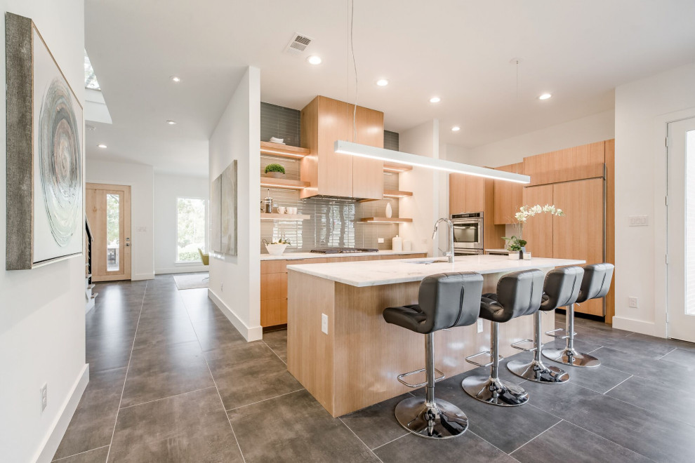 Foto di una cucina contemporanea con lavello sottopiano, ante lisce, ante in legno chiaro, paraspruzzi grigio, elettrodomestici da incasso, pavimento grigio e top bianco