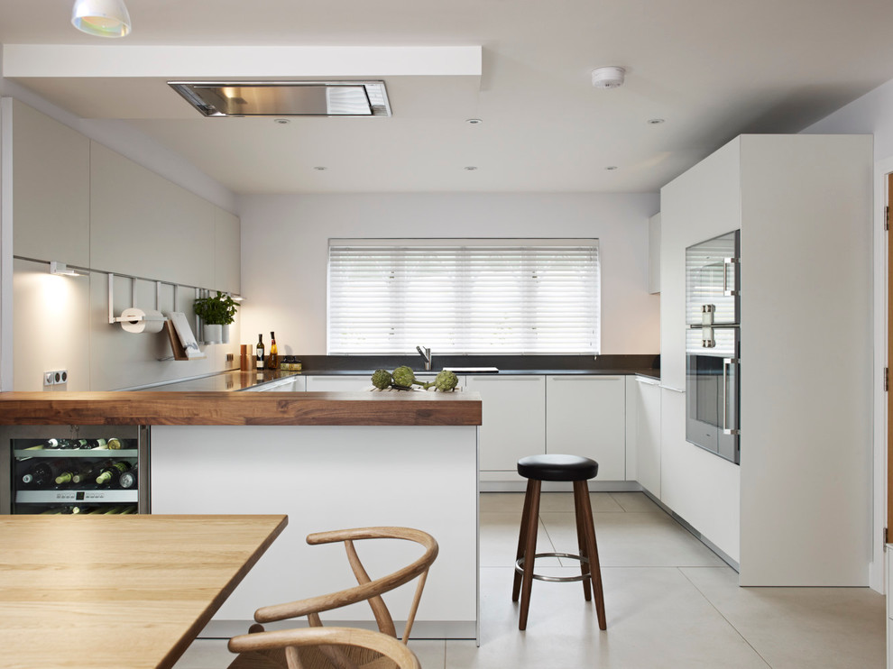 Diseño de cocina comedor contemporánea con armarios con paneles lisos, puertas de armario blancas, electrodomésticos de acero inoxidable y península