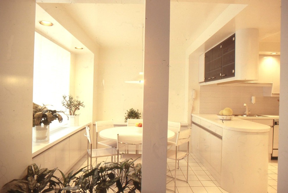 На фото: большая кухня в стиле модернизм с обеденным столом, двойной мойкой, плоскими фасадами, белыми фасадами, столешницей из ламината, разноцветным фартуком, фартуком из керамической плитки, белой техникой и полом из керамической плитки с