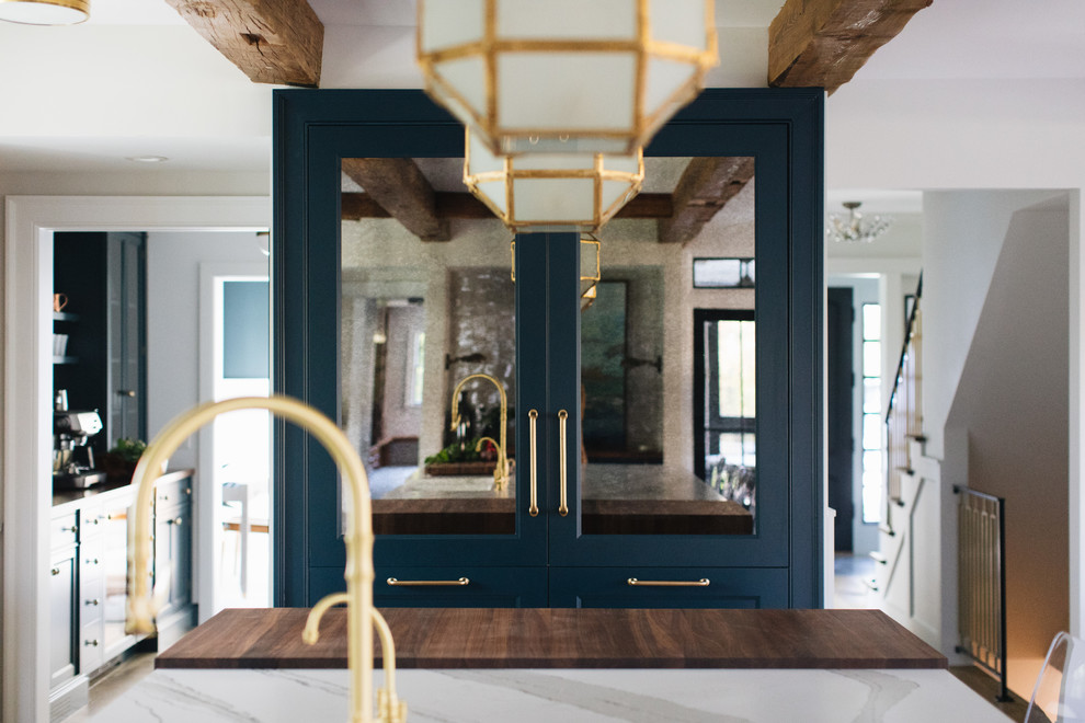 Idée de décoration pour une cuisine américaine parallèle tradition de taille moyenne avec un évier de ferme, un placard à porte shaker, des portes de placard bleues, un plan de travail en quartz modifié, un sol en bois brun, îlot et un sol marron.