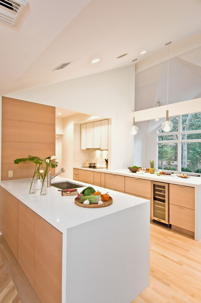 На фото: параллельная кухня в современном стиле с врезной мойкой, плоскими фасадами и светлыми деревянными фасадами с