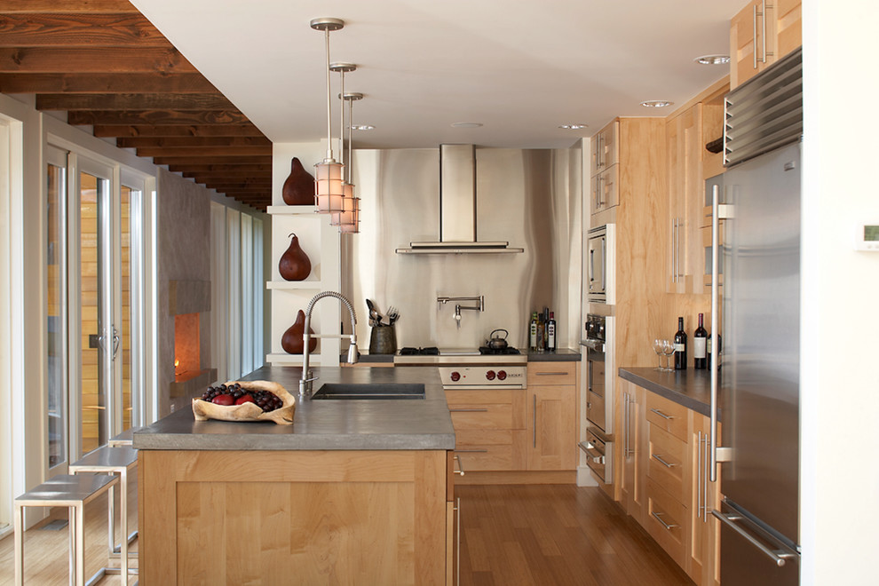 Inredning av ett modernt mellanstort kök, med skåp i shakerstil, skåp i ljust trä, bänkskiva i betong, grått stänkskydd, rostfria vitvaror, en köksö, en undermonterad diskho, stänkskydd i metallkakel och ljust trägolv