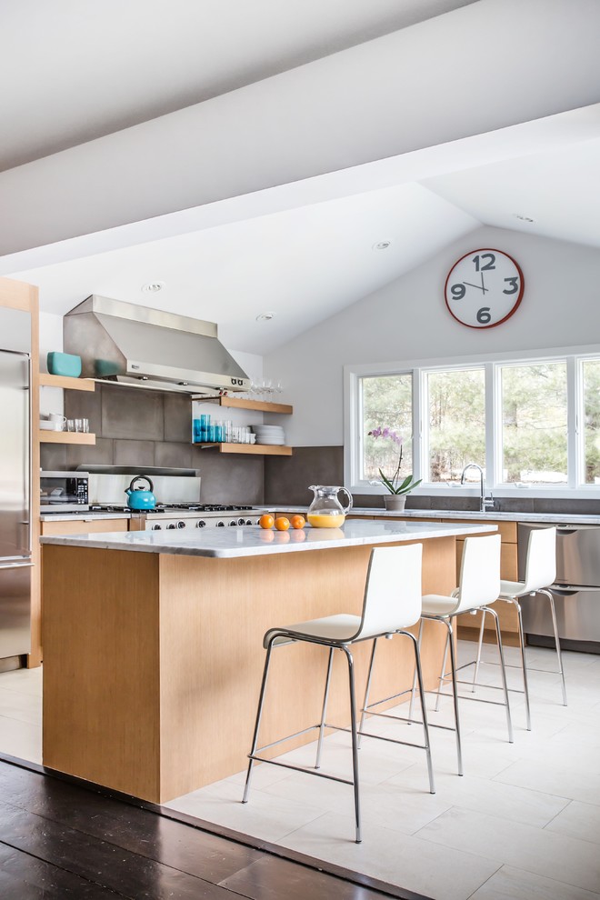 Moderne Küche in L-Form mit flächenbündigen Schrankfronten, hellen Holzschränken, Küchenrückwand in Grau, Küchengeräten aus Edelstahl und Kücheninsel in New York