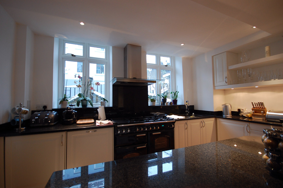 This is an example of a medium sized contemporary u-shaped kitchen/diner in London with a submerged sink, raised-panel cabinets, white cabinets, granite worktops, white splashback, ceramic splashback, integrated appliances, medium hardwood flooring and an island.
