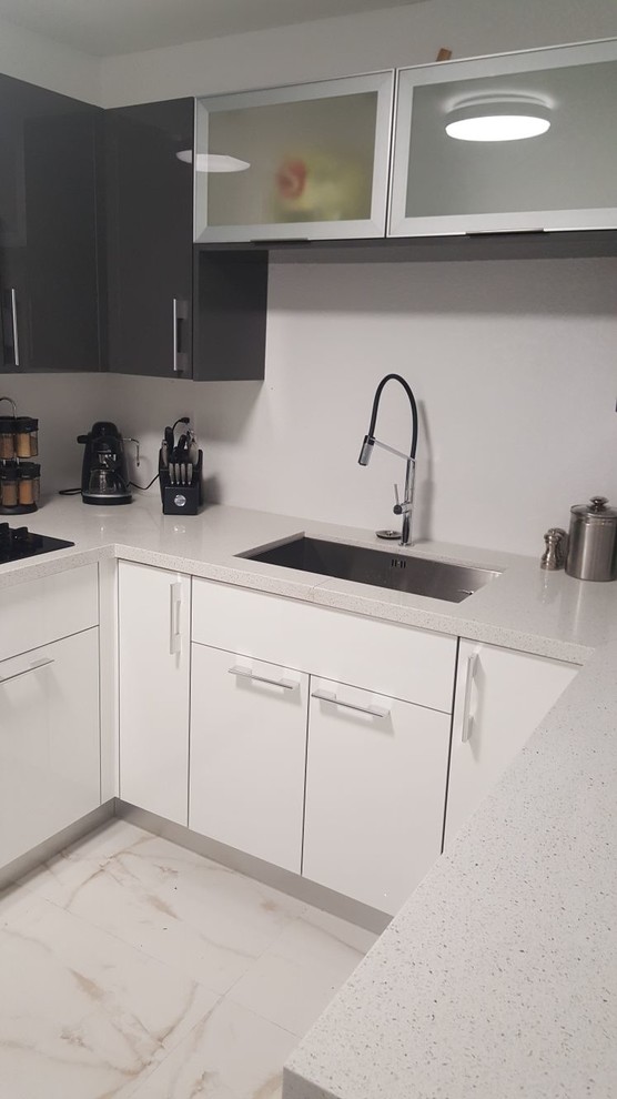 Foto di una cucina minimalista chiusa e di medie dimensioni con lavello sottopiano, ante lisce, ante bianche, top in quarzite, paraspruzzi grigio, paraspruzzi con lastra di vetro, elettrodomestici neri, pavimento in gres porcellanato, pavimento bianco e top bianco