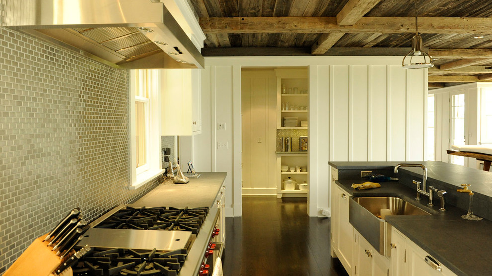 Exempel på ett mellanstort maritimt kök, med en rustik diskho, luckor med infälld panel, vita skåp, stänkskydd med metallisk yta, stänkskydd i metallkakel, rostfria vitvaror, mörkt trägolv och en köksö