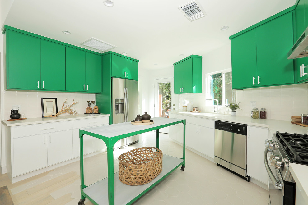 На фото: п-образная кухня в современном стиле с плоскими фасадами, зелеными фасадами, техникой из нержавеющей стали, островом, бежевым полом и белой столешницей