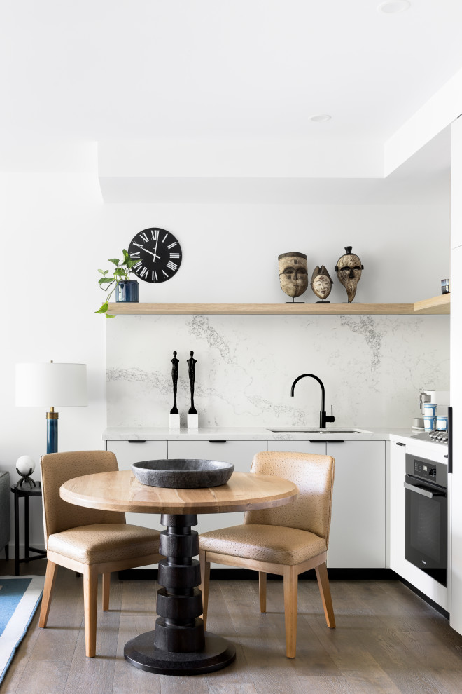 Example of a small trendy l-shaped gray floor eat-in kitchen design in Melbourne with an undermount sink, flat-panel cabinets, white cabinets, white backsplash, black appliances, no island and white countertops