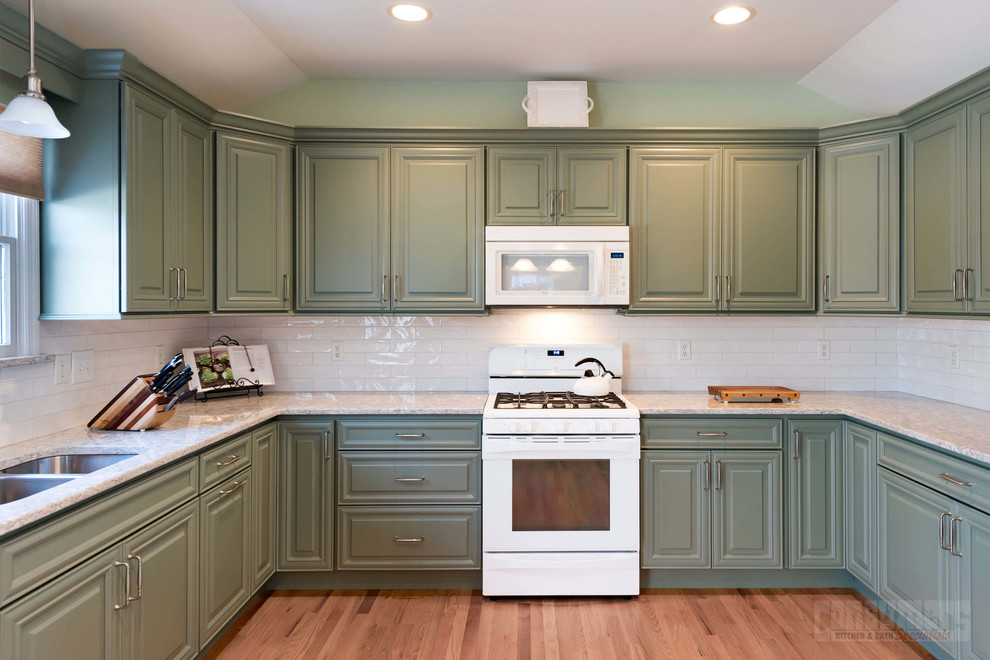 Exempel på ett mellanstort kök, med en undermonterad diskho, luckor med upphöjd panel, gröna skåp, bänkskiva i kvarts, vitt stänkskydd, stänkskydd i keramik, vita vitvaror, plywoodgolv, en köksö och beiget golv
