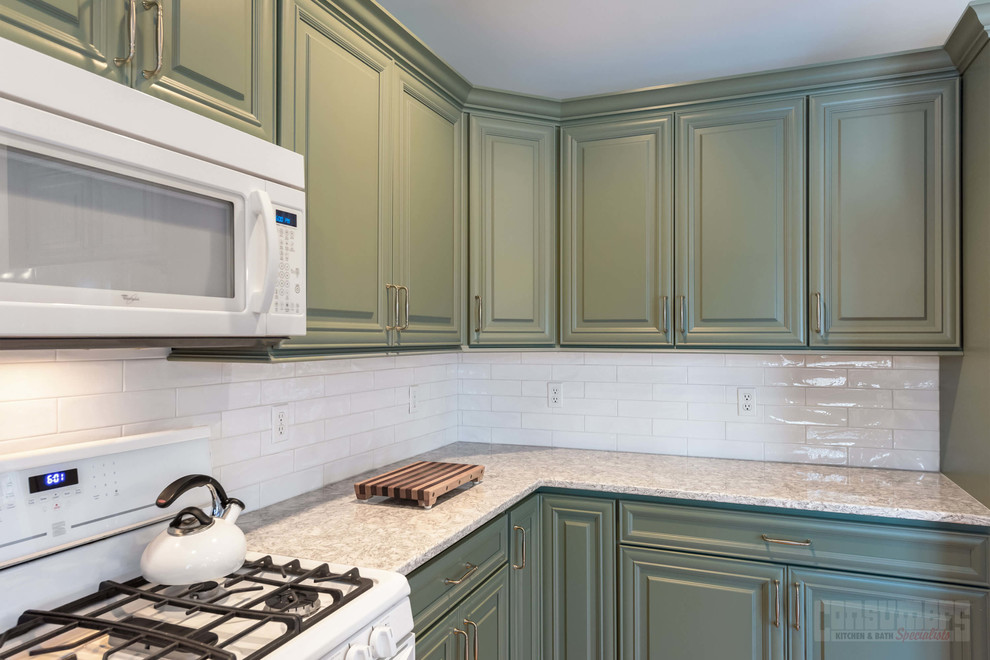 Inredning av ett mellanstort kök, med en undermonterad diskho, luckor med upphöjd panel, gröna skåp, bänkskiva i kvarts, vitt stänkskydd, stänkskydd i keramik, vita vitvaror, plywoodgolv, en köksö och beiget golv