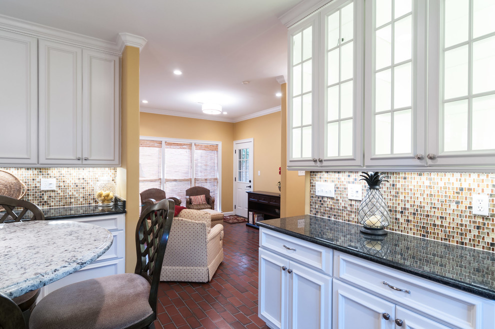 Example of a large classic u-shaped brick floor eat-in kitchen design in Other with a farmhouse sink, recessed-panel cabinets, white cabinets, quartz countertops, multicolored backsplash, mosaic tile backsplash, stainless steel appliances and an island