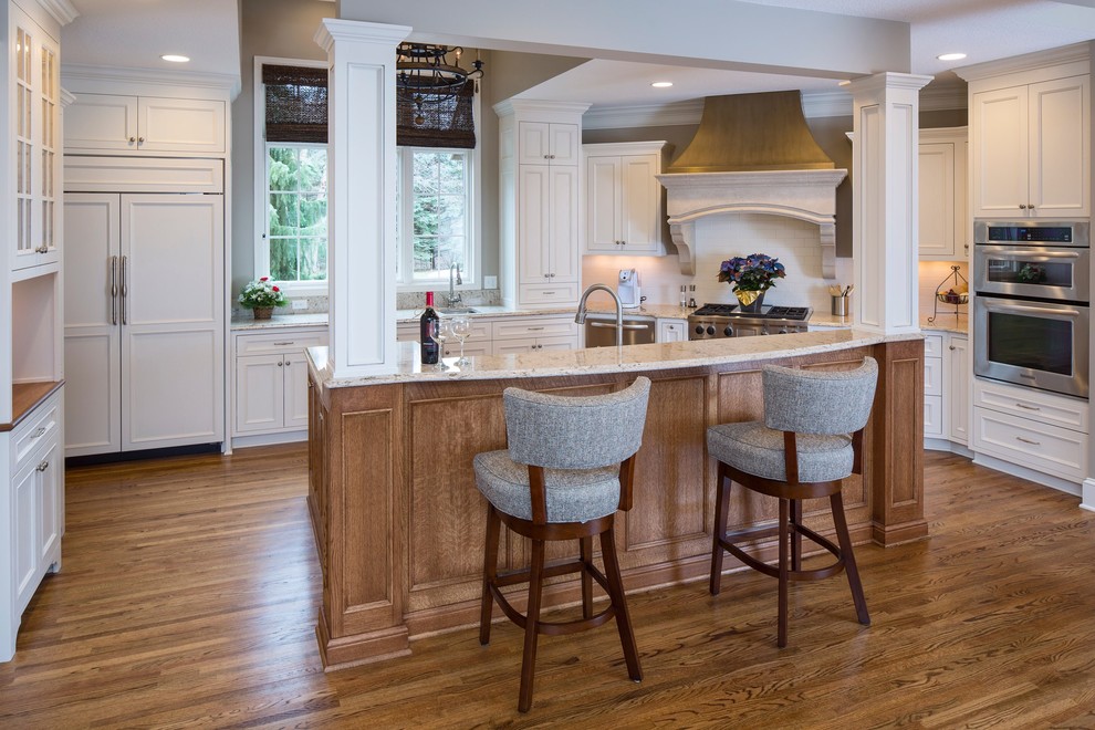 Inspiration for a traditional kitchen in Minneapolis with recessed-panel cabinets, white cabinets, white splashback, stainless steel appliances, medium hardwood flooring and an island.
