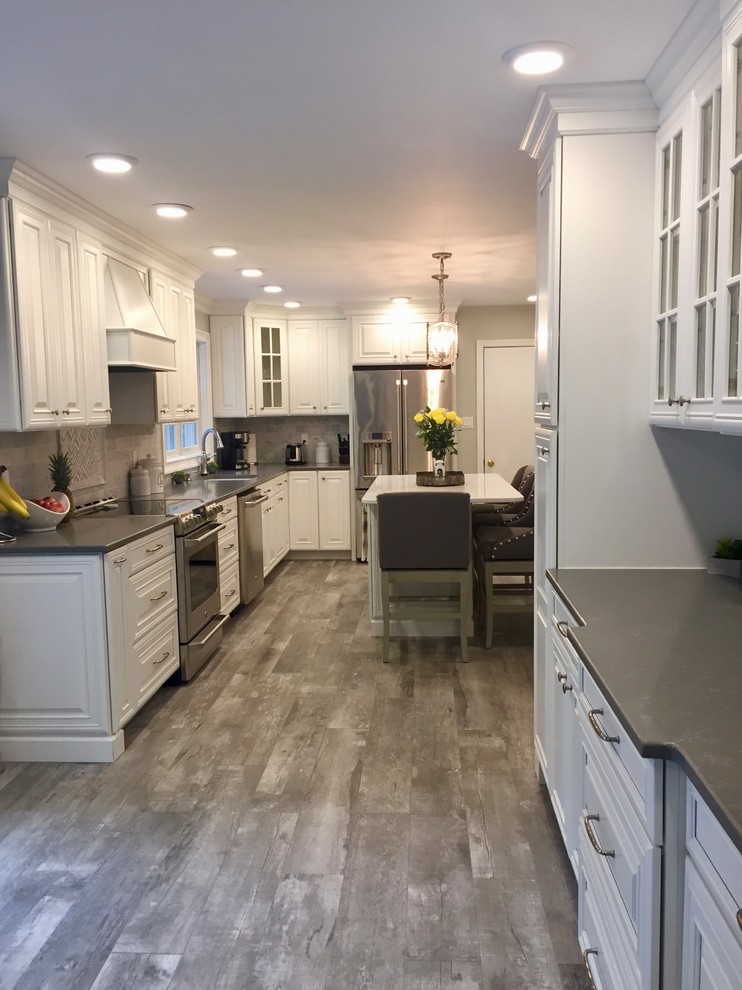 Design ideas for a traditional kitchen in New York with a submerged sink, raised-panel cabinets, white cabinets, engineered stone countertops, marble splashback, stainless steel appliances and an island.