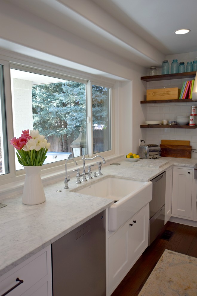 Photo of a large classic u-shaped open plan kitchen in Denver with a belfast sink, flat-panel cabinets, white cabinets, white splashback, ceramic splashback, stainless steel appliances, medium hardwood flooring and an island.