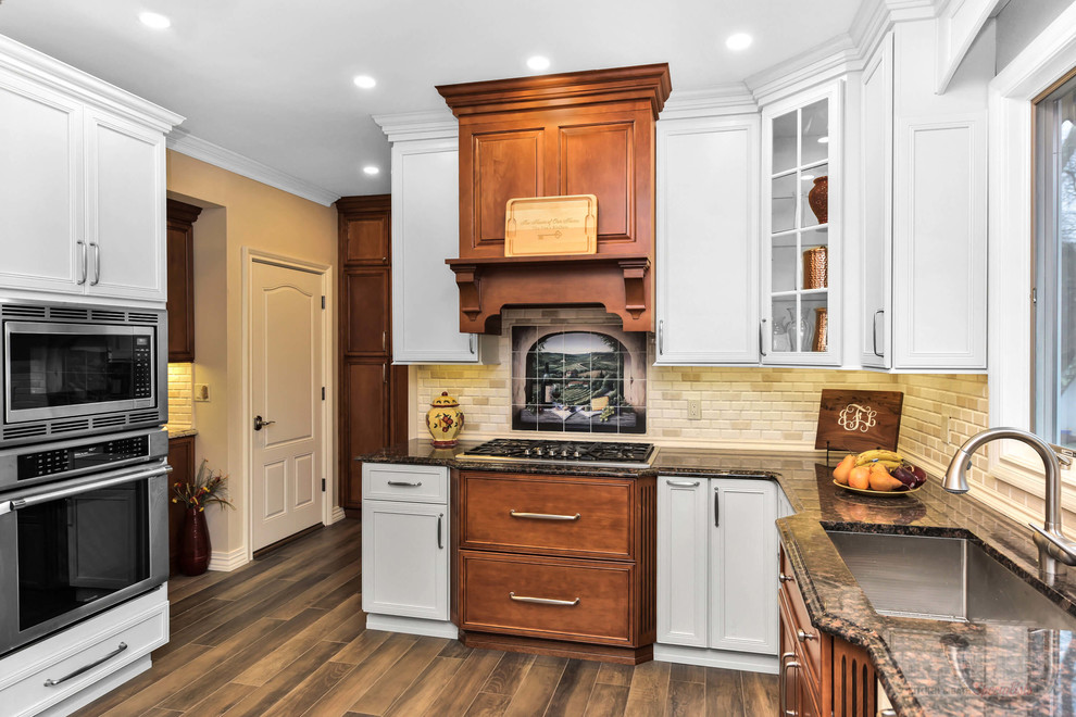 Mid-sized l-shaped eat-in kitchen photo in New York with an undermount sink, shaker cabinets, white cabinets, granite countertops, white backsplash, stainless steel appliances, no island and brown countertops