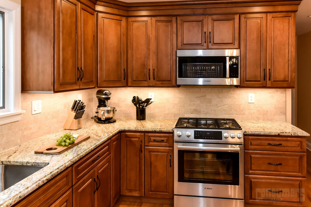 Exempel på ett mellanstort kök, med en undermonterad diskho, luckor med upphöjd panel, bruna skåp, granitbänkskiva, beige stänkskydd, rostfria vitvaror och en köksö