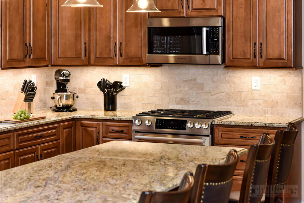 Foto di una cucina di medie dimensioni con lavello sottopiano, ante con bugna sagomata, ante marroni, top in granito, paraspruzzi beige e elettrodomestici in acciaio inossidabile