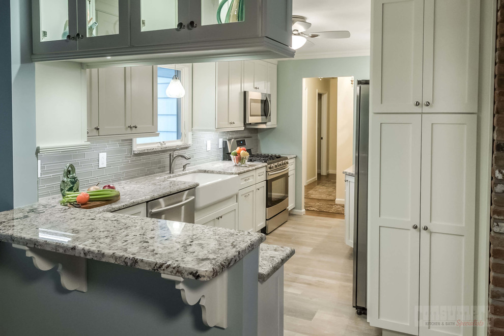 This is an example of a large galley kitchen/diner in New York with a belfast sink, recessed-panel cabinets, white cabinets, granite worktops, grey splashback, stainless steel appliances, plywood flooring and a breakfast bar.