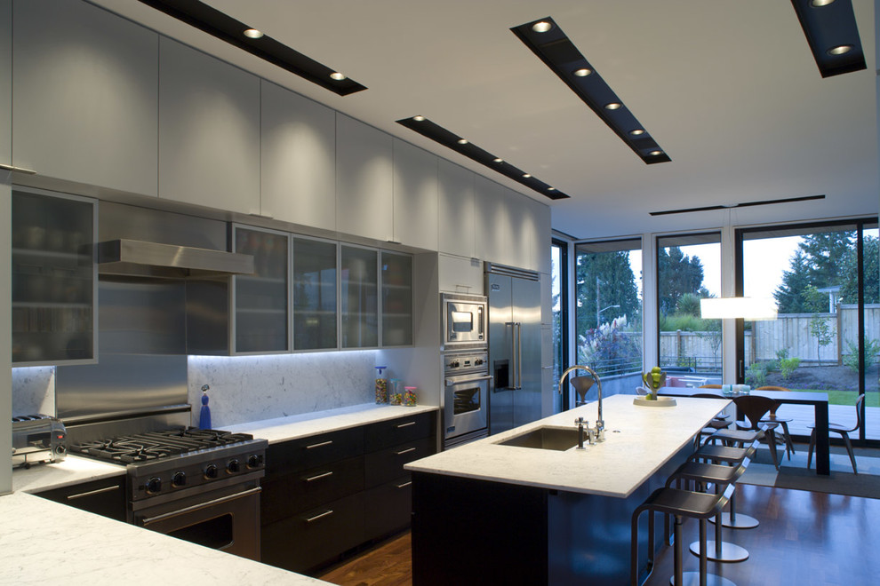 Foto de cocina comedor moderna con fregadero bajoencimera, armarios con paneles lisos, puertas de armario negras, encimera de mármol, salpicadero blanco, salpicadero de losas de piedra y electrodomésticos de acero inoxidable